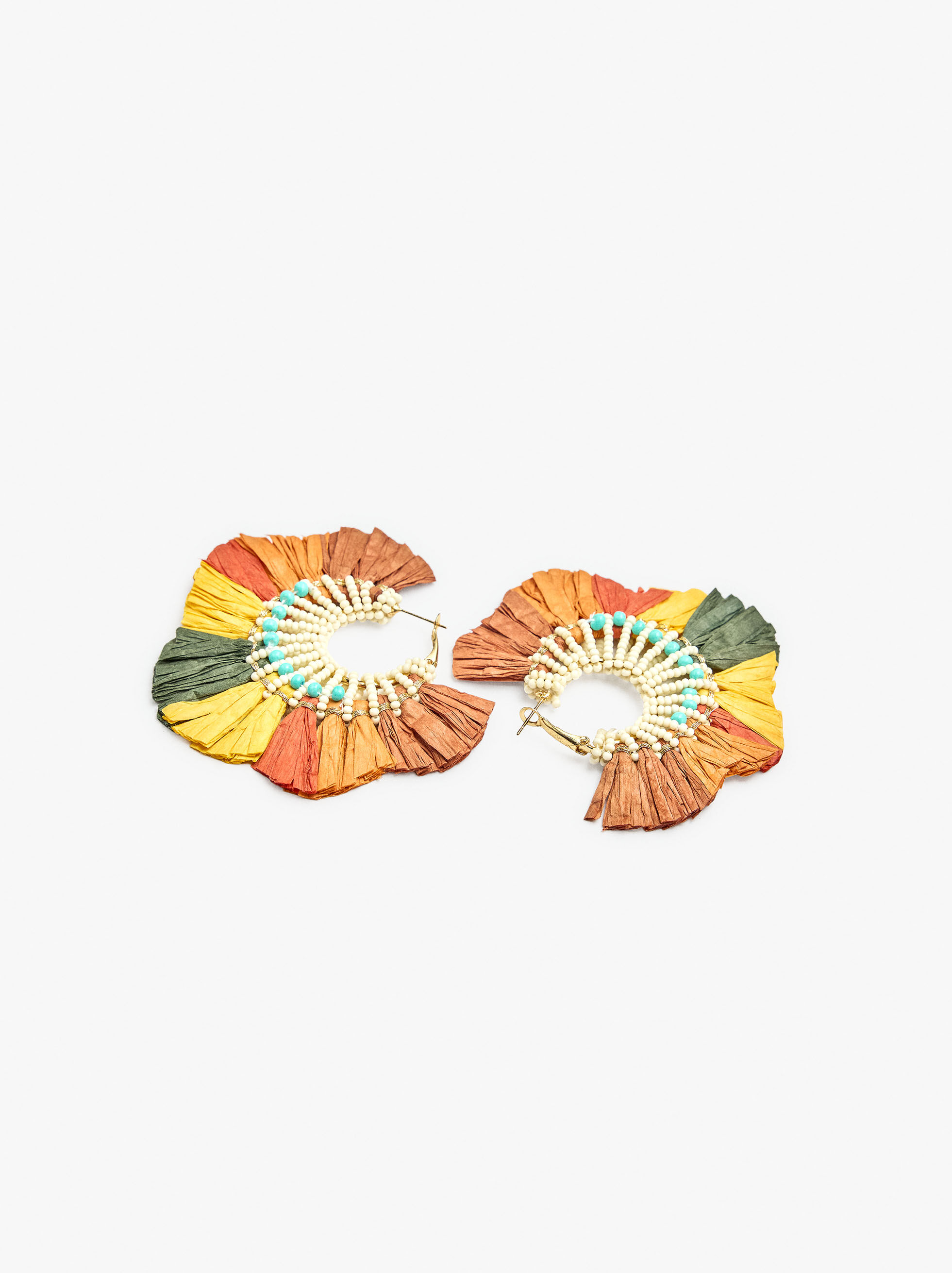 Argollas maxi con cuentas de vidrio entrelazadas y detalles en rafia multicolor en el borde exterior. Acabado dorado.